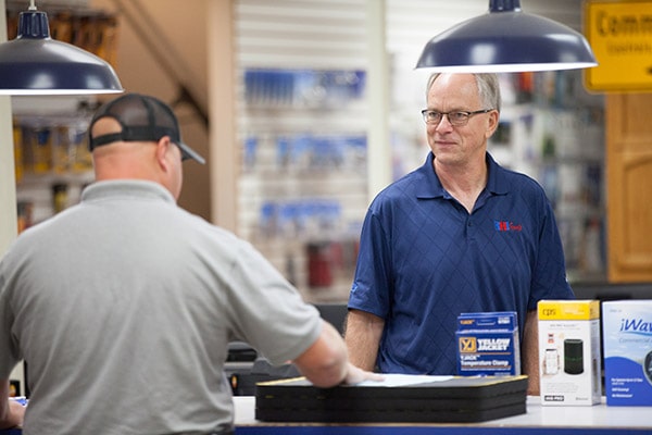 careers-sales-counter-min RHI employee working at sales desk helping HVAC/R customer.